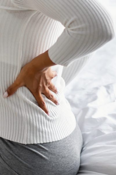 woman with back pain sitting on bed